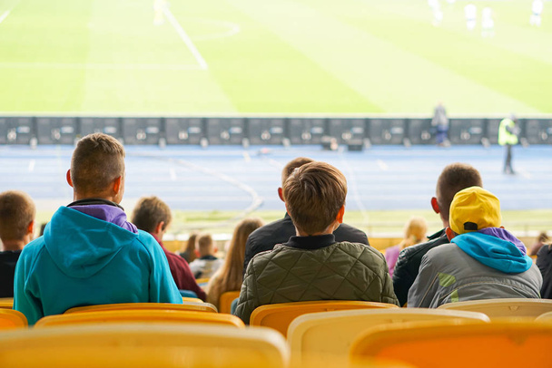 children watching while enjoying a game from seats for spectators in the stadium - Photo, Image