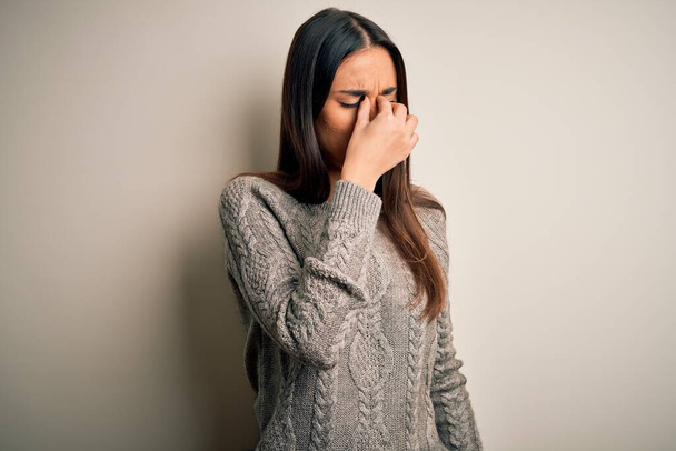 Young beautiful brunette woman wearing casual sweater over isolated white background tired rubbing nose and eyes feeling fatigue and headache. Stress and frustration concept. - Φωτογραφία, εικόνα