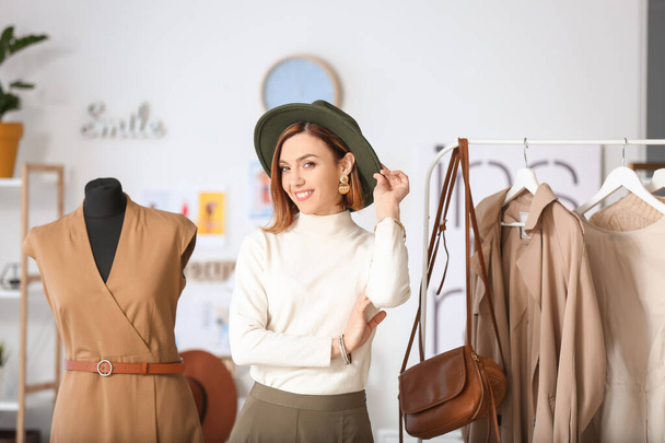 Female stylist near rack with modern clothes in her studio - Photo, image