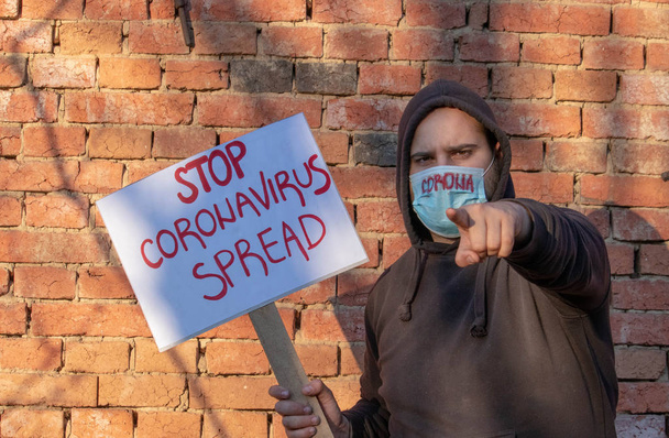 Homem com bandeira Stop Coronavirus Spread. O homem protesta, chamando os governos para ajudar a combater o vírus corona. A pessoa encoraja os cientistas a parar a pandemia. Pessoa com protesto de máscara
. - Foto, Imagem