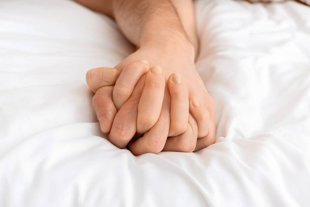 Handen van jong paar slapen in bed - Foto, afbeelding
