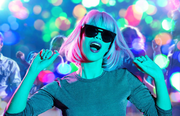 жінка в вігві і сонцезахисних окулярах танцює в нічному клубі
 - Фото, зображення