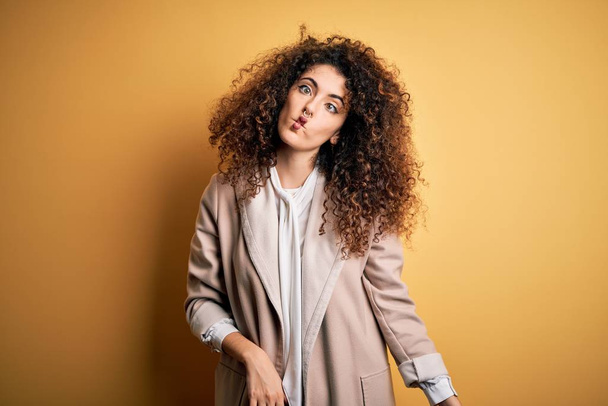 Young beautiful brunette woman with curly hair and piercing wearing casual t-shirt and diadem making fish face with lips, crazy and comical gesture. Funny expression. - Foto, Imagem