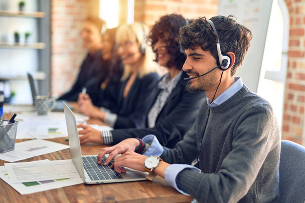Group of call center workers smiling happy and confident. Working together with smile on face using headset at the office. - Foto, imagen