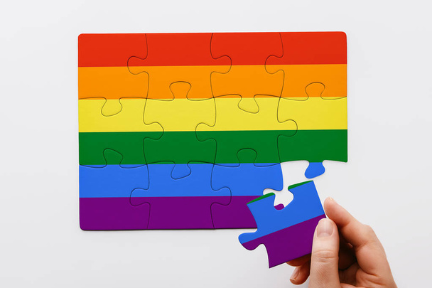 LGBT-käsite. Käsi laittaa viimeinen pala sateenkaaren värillinen palapeli. Homoylpeys. Yläkuva
  - Valokuva, kuva