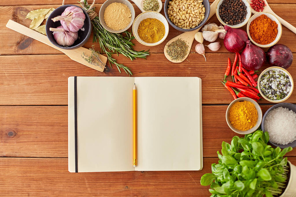 notebook with pencil among spices on wooden table - Foto, afbeelding