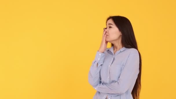 Young girl Asian girl crying on a yellow background. a woman is upset - Felvétel, videó