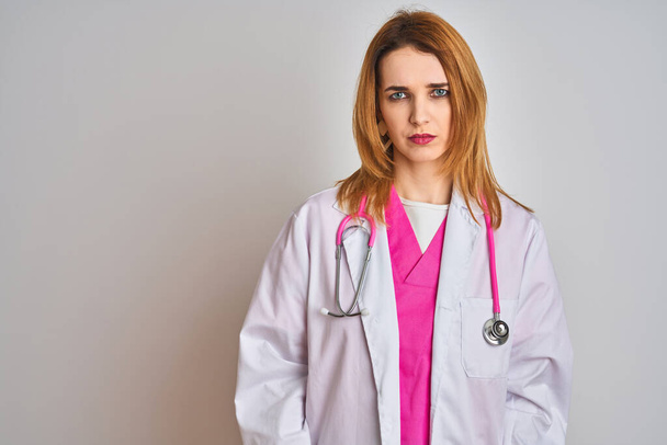 Redhead caucasian doctor woman wearing pink stethoscope over isolated background skeptic and nervous, frowning upset because of problem. Negative person. - Foto, Bild