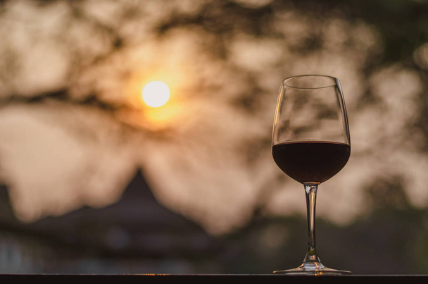 夕日を背景にテーブルの上に赤ワインのガラス. - 写真・画像