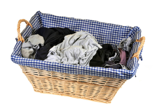 Schmutzige Wäsche in einem Weidenkorb in Großaufnahme auf weißem Hintergrund  - Foto, Bild