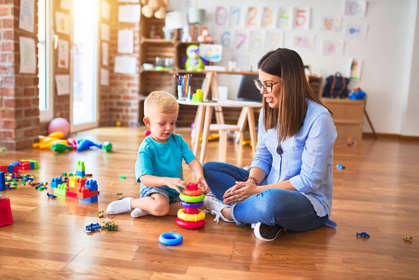 若い白人の子供は教師と一緒に学校で遊んでいる。母親と息子とともにplayroomとともにインテリジェンスおもちゃ - 写真・画像