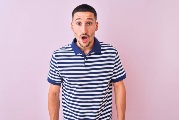 Young handsome man wearing nautical striped t-shirt over pink isolated background afraid and shocked with surprise expression, fear and excited face. - Photo, Image