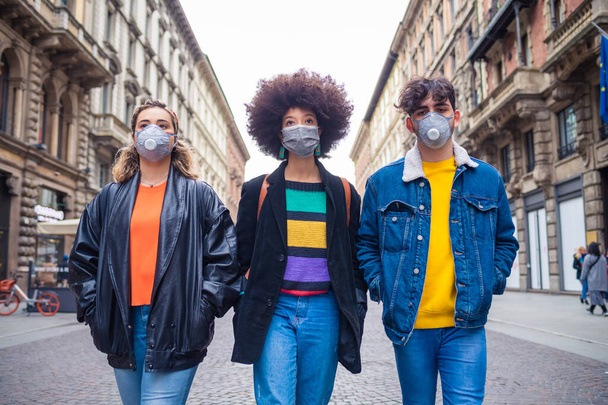 汚染やウイルスから守る医療マスクを身に着けている3人の多民族の友人-抗スモッグ、感染症、抗議の概念 - 写真・画像