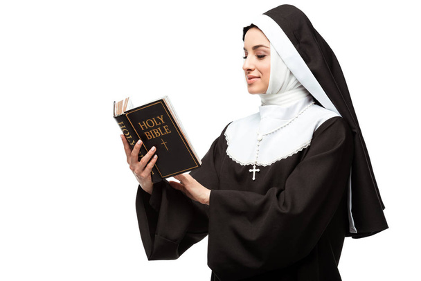 beautiful smiling nun holding holy bible isolated on white - 写真・画像