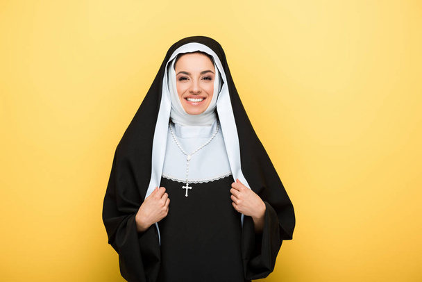 mooie vrolijke non kijkend naar camera, op geel - Foto, afbeelding