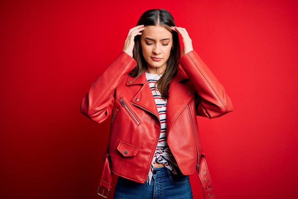 Young beautiful brunette woman wearing casual jacket standing over red background with hand on head for pain in head because stress. Suffering migraine. - Photo, Image