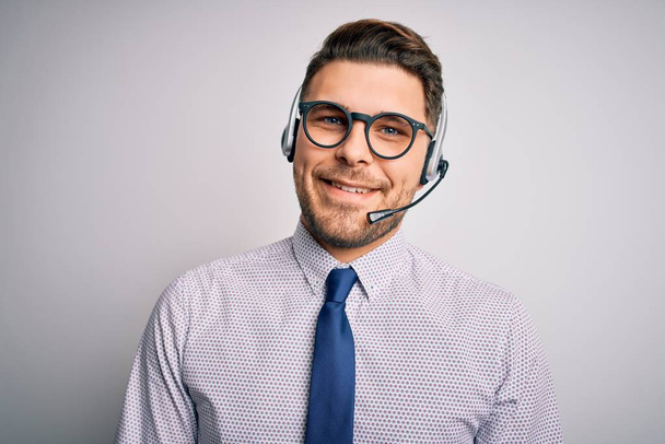 Młody operator call center biznesmen z niebieskimi oczami, noszący okulary i słuchawki z uśmiechem na twarzy. Szczęśliwy człowiek.. - Zdjęcie, obraz