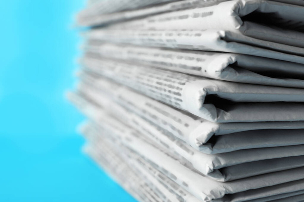 Stapel kranten op lichtblauwe achtergrond, close-up. Journalistenwerk - Foto, afbeelding