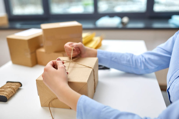 woman packing parcel and tying rope at post office - Foto, Imagem