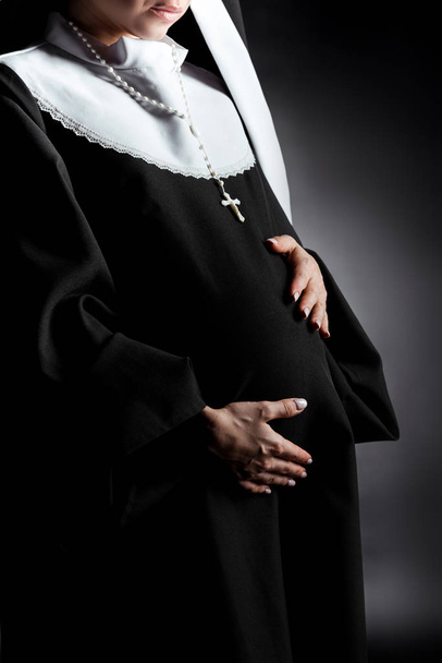 cropped view of pregnant nun touching tummy on grey - Photo, Image