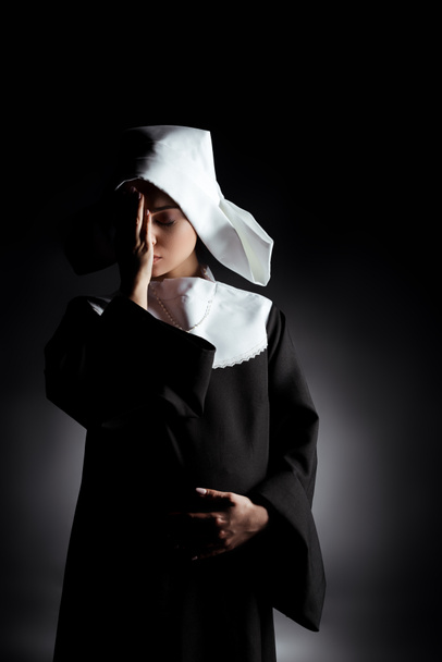 upset tired pregnant nun with closed eyes standing on grey - Foto, Bild