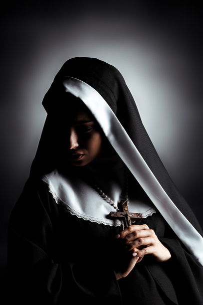 hermosa joven monja triste sosteniendo cruz en gris
 - Foto, imagen