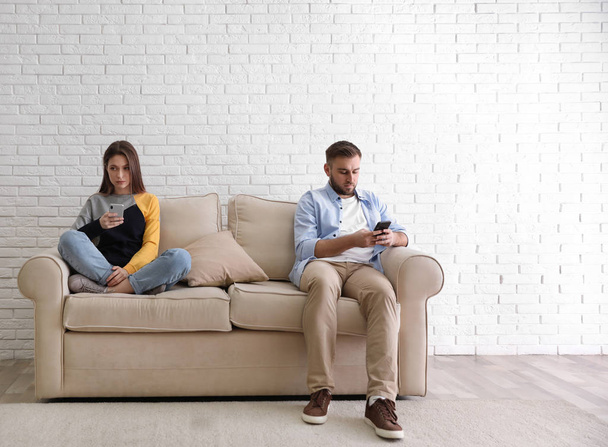 Couple addicted to smartphones ignoring each other at home. Relationship problems - Zdjęcie, obraz