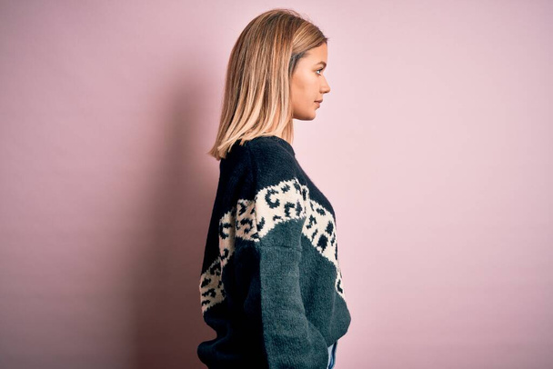 Young beautiful blonde woman wearing fashion sweater over pink isolated background looking to side, relax profile pose with natural face with confident smile. - 写真・画像