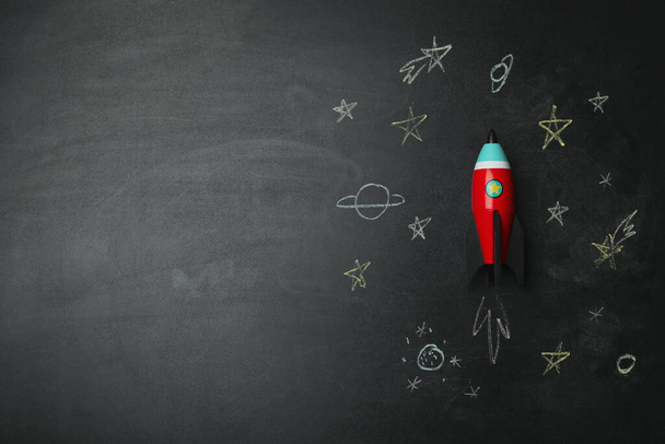 Bright toy rocket and drawings on chalkboard, flat lay. Space for text - 写真・画像