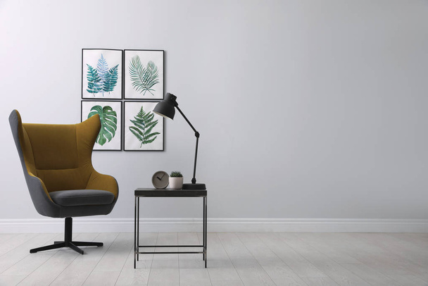 Stylish room interior with comfortable armchair and paintings of tropical leaves. Space for text - Photo, Image