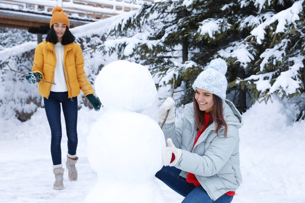 Happy friends making snowman outdoors. Winter vacation - Fotoğraf, Görsel