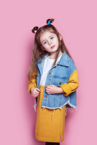 Cute little girl model in denim on pink background. Fashion concept - Photo, Image