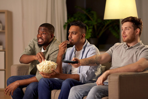 mężczyzna przyjaciele z popcorn oglądanie telewizji w domu - Zdjęcie, obraz