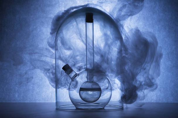 Chemical reaction in glassware on blue background. Flasks with liquid and smoke. Chemical laboratory, science concept. Creative glassware. Copy space - Photo, image
