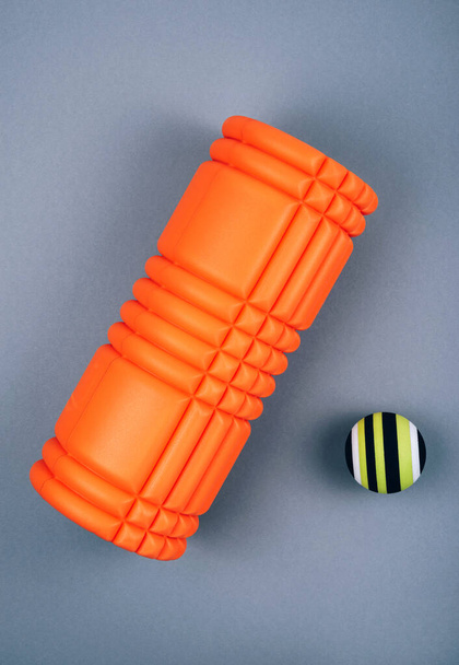 緑の筋膜放出とマッサージボール、グレーの背景にトリガーポイントのためのオレンジ色のでこぼこ泡マッサージローラーのセット。セルフボディケアマッサージとストレス、痛みの軽減。スポーツコンセプト. - 写真・画像