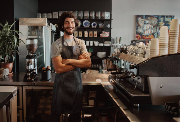 Successful male business owner behind the counter of a coffee shop with folded hands smiling looking at camera - Fotoğraf, Görsel