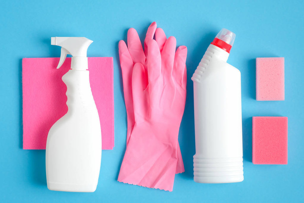Set of cleaning supplies on blue background. Flat lay pink rag and sponge, rubber gloves, cleaner spray bottle, detergent. House cleaning service and housekeeping concept - Fotografie, Obrázek