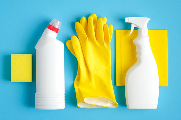 Mavi arka planda temizlik malzemeleri var. Düz sarı bez ve sünger, lastik eldivenler, daha temiz sprey şişesi, deterjan. Ev temizliği ve temizlik konsepti - Fotoğraf, Görsel