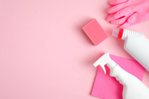 Cleaning supplies on pink background. Top view cleaner spray bottle, rag, sponge, detergent, rubber gloves. House cleaning service and housekeeping concept - Foto, Bild