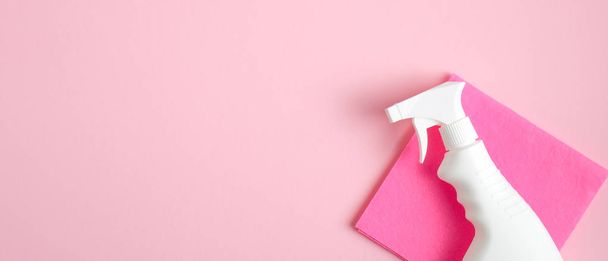 Cleaner spray bottle and rag on pink background. Cleaning service banner mockup. Housecleaning and housekeeping concept. Flat lay, top view - 写真・画像