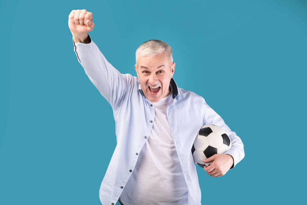 Mann posiert mit Fußball auf blauem Hintergrund - Foto, Bild