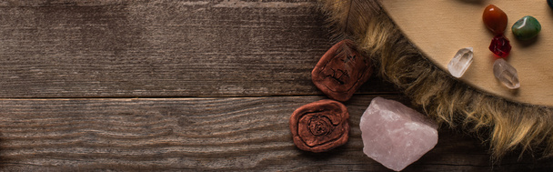 Top view of crystals, clay amulets and tambourine on wooden surface, panoramic shot - Photo, Image
