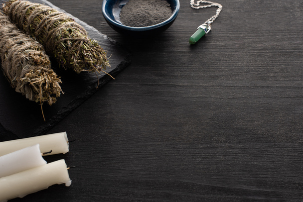 Velas, varas de mancha com cristal e tigela de cinzas na superfície de madeira escura
 - Foto, Imagem