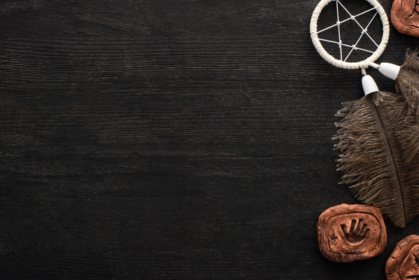 Top view of clay amulets and shamanic dreamcatcher on dark wooden surface - 写真・画像
