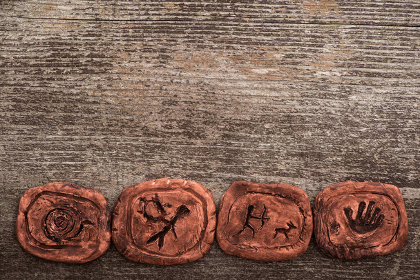 Top view of shamanic clay talismans on wooden background - Foto, imagen