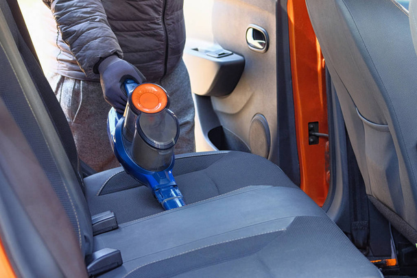 Czyszczenie wnętrza samochodu z niebieskim odkurzaczem. Tekstylne fotele samochodowe są regularnie sprzątane. - Zdjęcie, obraz