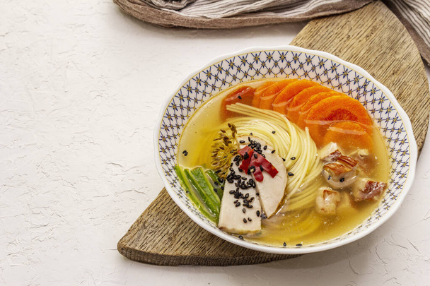 Koreai tésztaleves füstölt csirkével és zöldségekkel. Fűszeres étel az egészséges étkezéshez. Fehér gitt textúra háttér, közelről - Fotó, kép