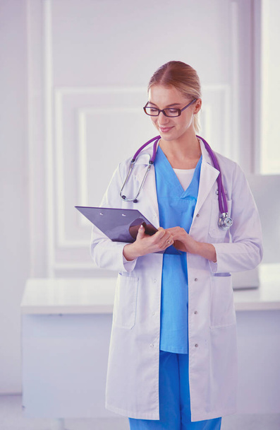 Smiling female doctor with a folder in uniform standing - Zdjęcie, obraz