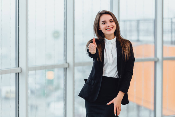 Pretty office employee showing thumb up isolated near window. - Photo, Image