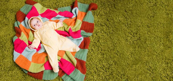 Pequeno bebê está em cobertor colorido
 - Fotografia, imagem
